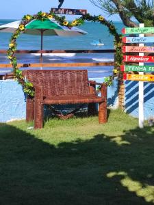 eine Korbbank unter einem Sonnenschirm am Strand in der Unterkunft Restaurante & Pousada Portal dos Ventos in Icapuí