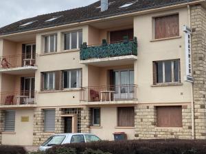 a building with a car parked in front of it at Les studios meublés de la résidence Beatrice in Bourbonne-les-Bains