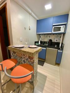 a kitchen with blue cabinets and a counter with orange chairs at Aconchego com vista mar in Vila Velha