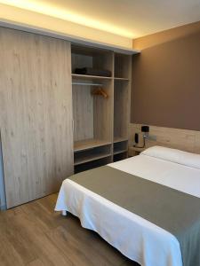 1 dormitorio con cama blanca y armarios de madera en Hotel Mestral Perelló en Perelló