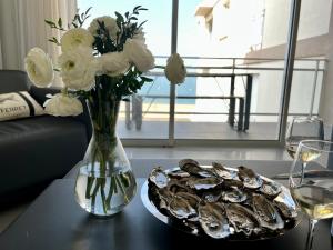 eine Vase aus Blumen und ein Teller Austern auf dem Tisch in der Unterkunft L'OCEAN vue bassin 1ère ligne Plage Pereire vue mer in Arcachon