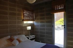 1 dormitorio con 1 cama con lámpara y ventana en Casa Xanelas, casa de playa en Punta Rubia, Rocha, en La Pedrera