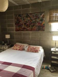 ein Schlafzimmer mit einem Bett und einem Gemälde an der Wand in der Unterkunft Casa Xanelas, casa de playa en Punta Rubia, Rocha in La Pedrera
