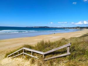 a wooden bench sitting on a sandy beach at Apartamento San Martín in Sanxenxo
