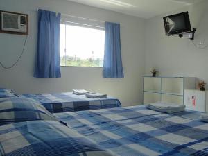伊塔布纳Hotel Pousada Positiva的一间卧室设有两张床,窗户配有电视。