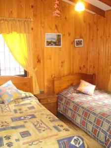 two beds in a room with wood paneled walls at Cabañas La Cumbre in Licán Ray