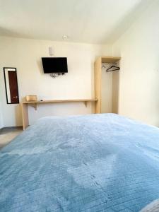 - une chambre avec un lit et une télévision murale dans l'établissement Hotel Hai Do, à Bernal