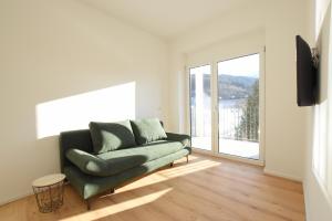 a living room with a green couch and a window at myQuartier Central City Suites in Innsbruck