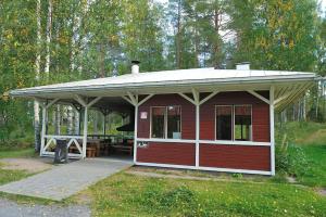 a red cabin with a roof and a picnic table at Hännilänsalmi Camping in Viitasaari