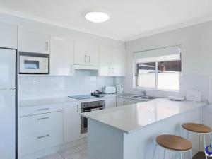 
a kitchen with white cabinets and white appliances at Sapphire Waters Unit 3 in Narooma
