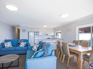 a living room with a blue couch and a table at Sapphire Waters Unit 3 in Narooma
