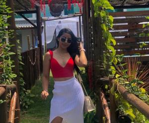 a woman wearing a red crop top and a white skirt at Pousada dos Duques in Prado