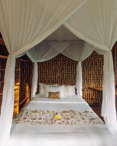 een slaapkamer met een hemelbed bij Temple House 3bds Eco Bamboo House Pool River View in Bringkit