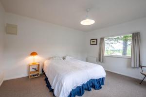 a white bedroom with a bed and a window at 15 Bristol Street in Hanmer Springs