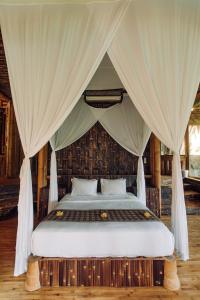 een slaapkamer met een hemelbed bij Temple House 3bds Eco Bamboo House Pool River View in Bringkit