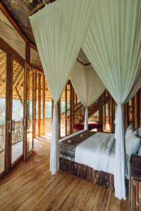 een slaapkamer met een bed met gordijnen bij Temple House 3bds Eco Bamboo House Pool River View in Bringkit