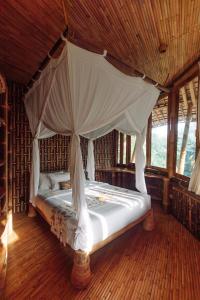 een hemelbed in een kamer met houten vloeren bij Temple House 3bds Eco Bamboo House Pool River View in Bringkit