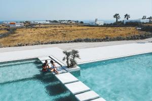 a group of three people standing next to a swimming pool at Adama Mykonos Boutique Hotel in Mikonos