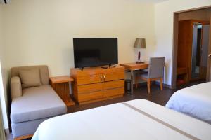 Habitación de hotel con TV, cama y escritorio. en Saipan Beach Hotel, en Saipán