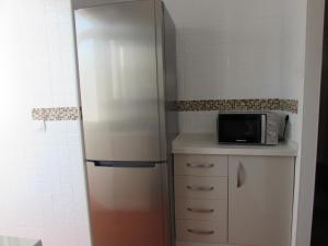 una cucina con frigorifero e forno a microonde su un bancone di Luz y Mar Huelva-Ático a Huelva