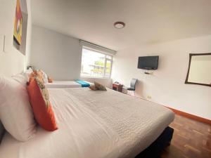 a bedroom with a large white bed with a window at Hotel Arena Plaza Inn in Bogotá