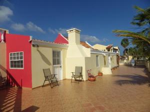 鷹海灘的住宿－阿魯巴昆庫公寓式酒店，白色和红色的房子,在庭院里摆放着椅子