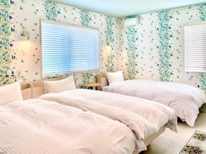 2 camas en un dormitorio con papel pintado con motivos florales en Sparky’s House, en Naoshima
