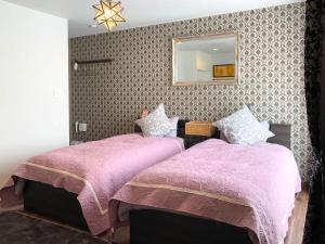 a bedroom with two beds with purple blankets and a mirror at Sparky’s House in Naoshima