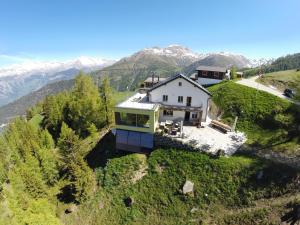 an aerial view of a house on a hill with mountains at Berggasthaus Wasenalp in Brig