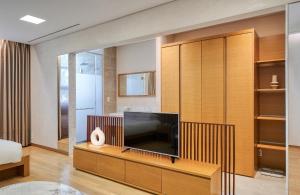 a living room with a television on a wooden cabinet at Mayfield Hotel Seoul in Seoul