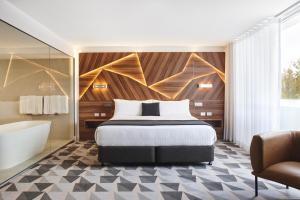 格里菲斯The Gem Hotel的一间卧室配有一张床、一个浴缸、一张床和一把椅子