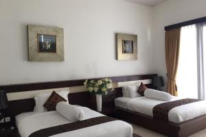 Una habitación de hotel con dos camas y una ventana. en Aldeoz Villa Nusa Dua, en Nusa Dua 7 fotos más