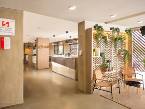 a lobby with chairs and a counter with plants at Swiss-Belexpress Cilegon in Cilegon