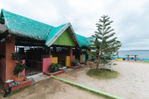 ein Haus am Strand mit einem Baum davor in der Unterkunft RGV Beach Resort Batangas in Calatagan