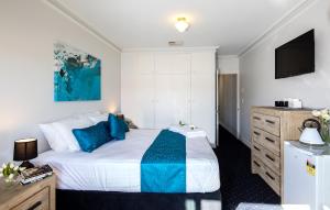 a bedroom with a large bed with blue pillows at Charm on Carrington in Adelaide