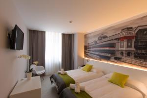 una camera d'albergo con due letti e un dipinto sul muro di Bilbao City Rooms a Bilbao