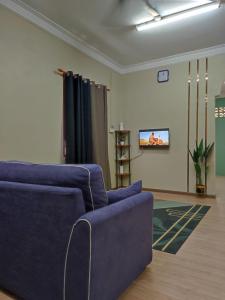 a living room with a blue couch and a tv at Kubang Kerian DECO HOMESTAY Aircond Wifi Netflix in Kota Bharu