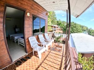 a balcony with two white chairs and a bed at JR&GYM Resort in Phi Phi Islands