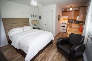 a bedroom with a white bed and a black chair at Studiotel Bromont in Bromont