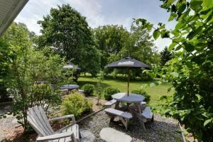 - une table, des chaises et un parasol dans la cour dans l'établissement Studiotel Bromont, à Bromont