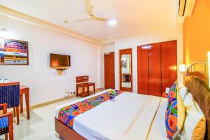 um quarto com uma cama, uma secretária e uma televisão em FabHotel F9 NFC em Nova Deli