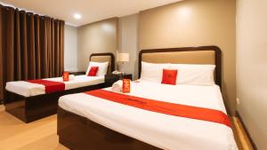 a hotel room with two beds with red pillows at RedDoorz Plus Park-Lay Suites Kidapawan City in Kidapawan