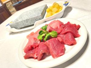 a white plate of meat on a table at Albergo La Perla in Craveggia