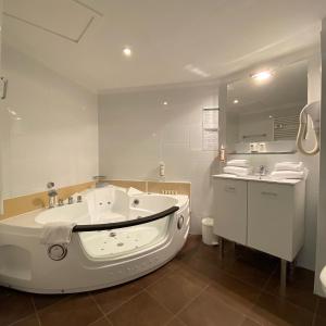 a white bathroom with a tub and a sink at The Originals City, Hôtel Les Dômes, Perpignan Sud Saleilles in Perpignan