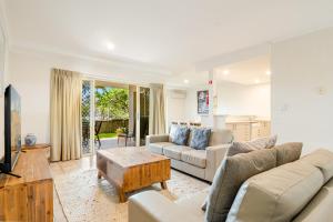 a living room with a couch and a table at Byron Bay Beach Apartments in Byron Bay