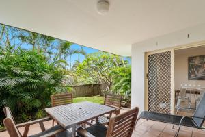 a patio with a wooden table and chairs on a porch at Byron Bay Beach Apartments in Byron Bay
