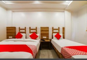 two beds in a room with red pillows at Hotel Awesome International in New Delhi