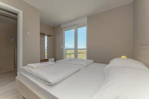 a white bedroom with two beds and a window at Apartment Amazing Island in Povljana +25 photos