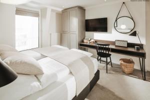 a white bedroom with a desk and a bed at Villa Breeksee in Norderney