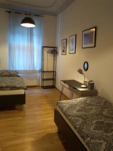 een slaapkamer met 2 bedden en een bureau met een lamp bij Ferienwohnungen in der Kunstgalerie Charlie und Jenny in Chemnitz